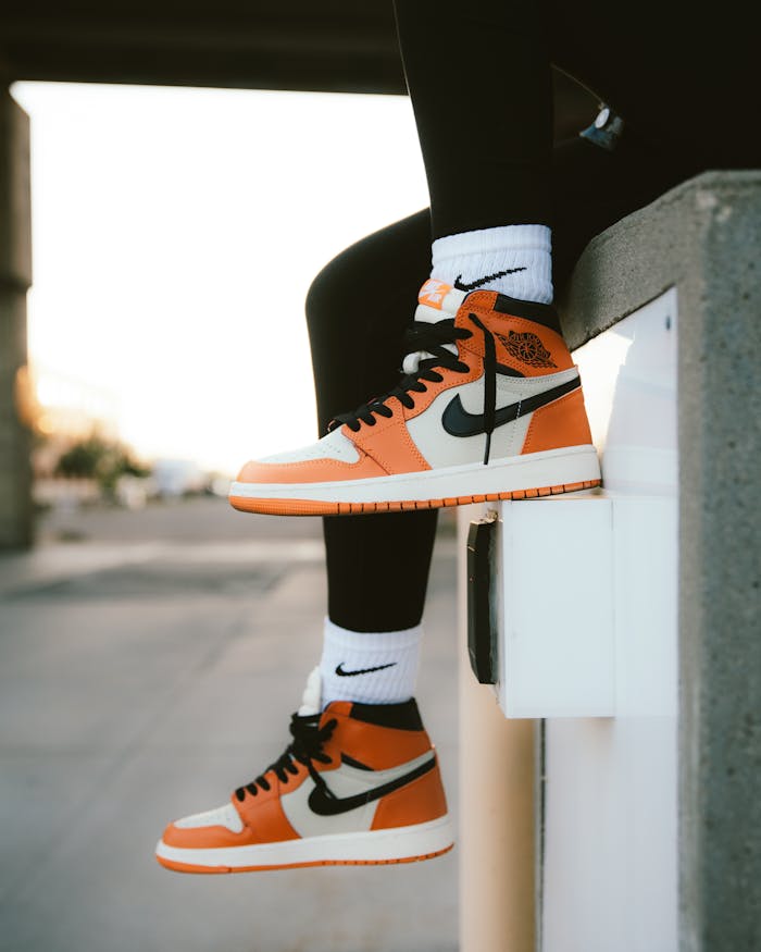 Close-up of orange sneakers and socks against an urban backdrop, highlighting street fashion.
