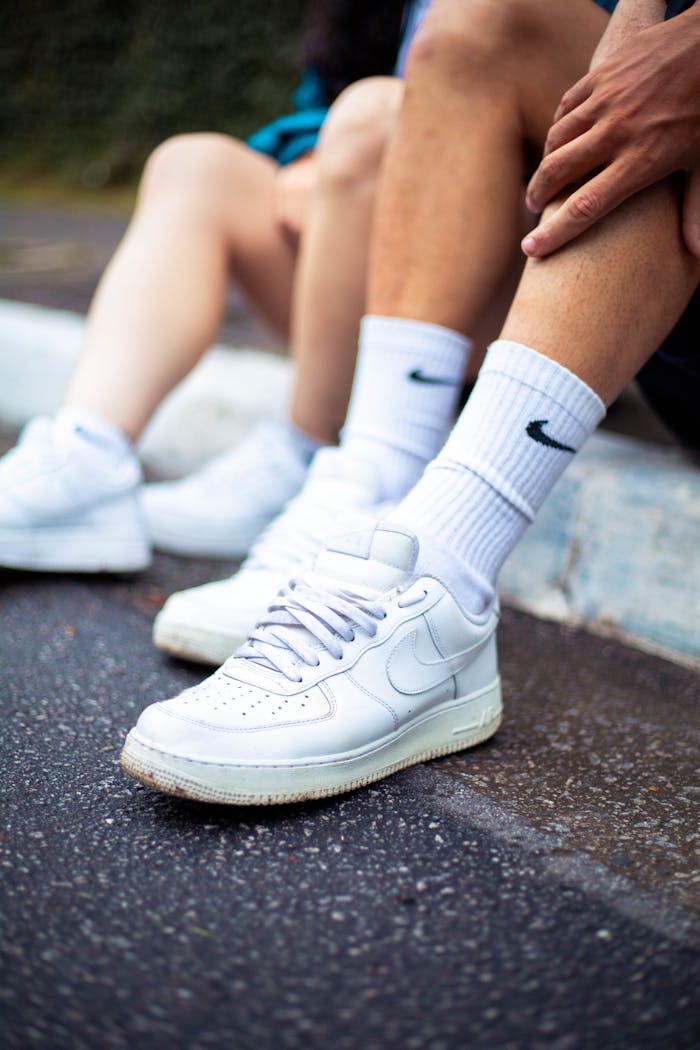 Close-up of sporty white sneakers and socks on a city curb.