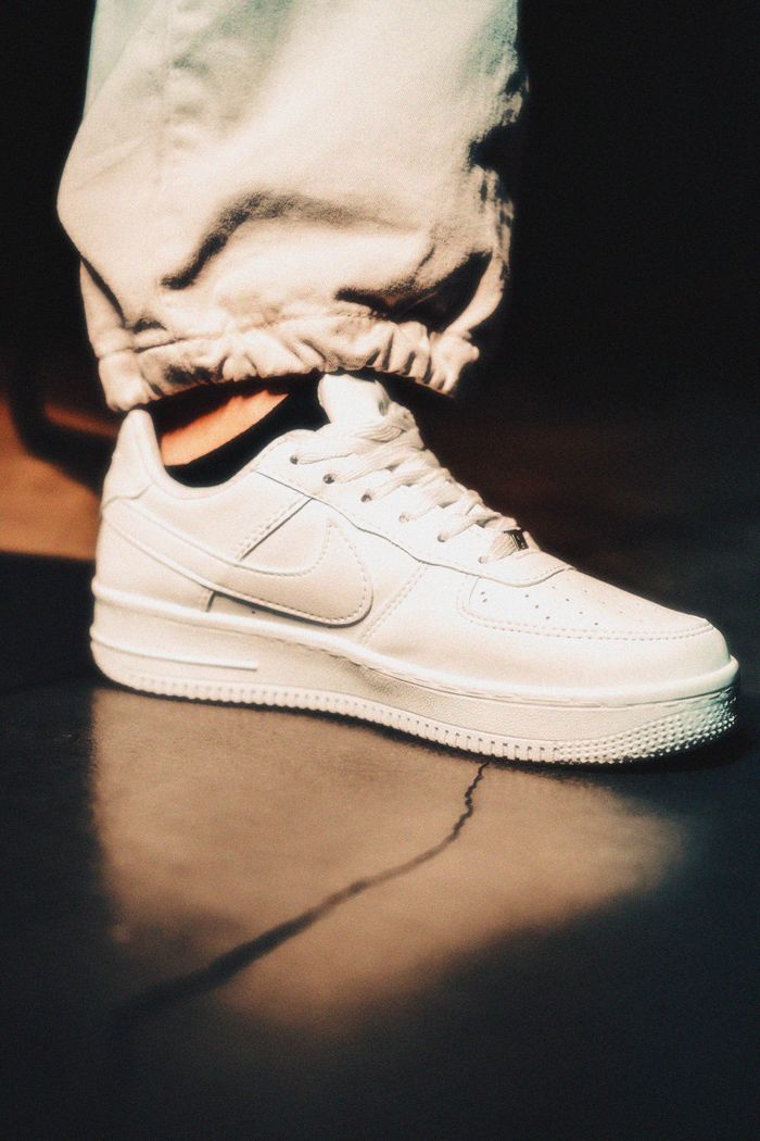Fashion-forward close-up of white sneakers on a textured floor showcasing footwear style.